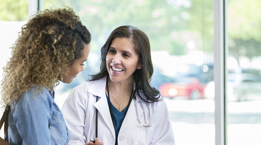 Female doctor discusses something with young mixed race patient